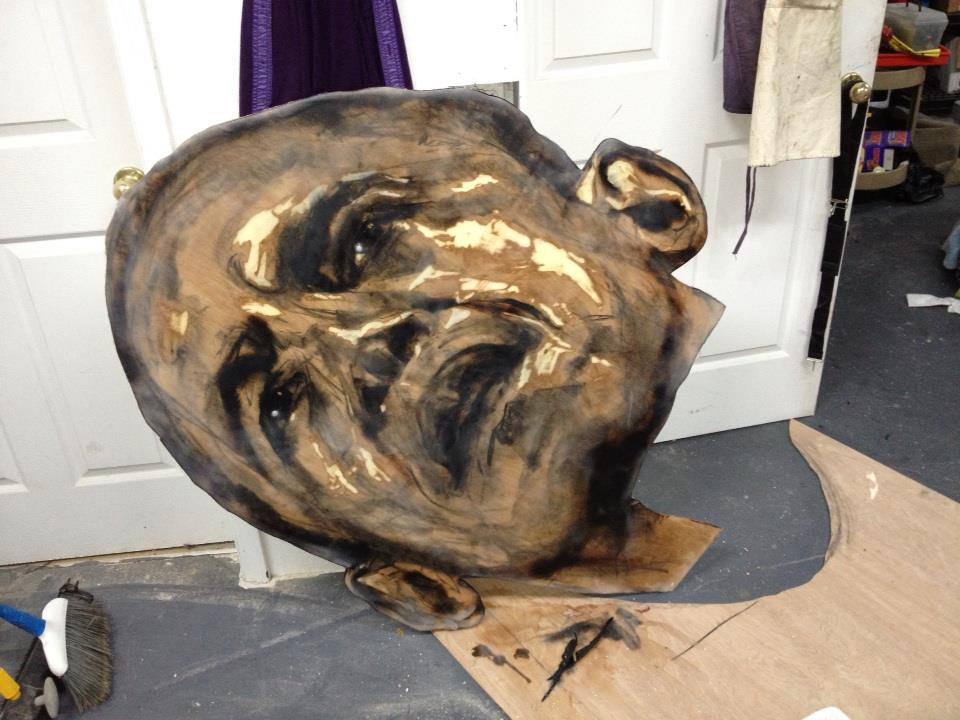 A cut-out painted head standing on the studio floor