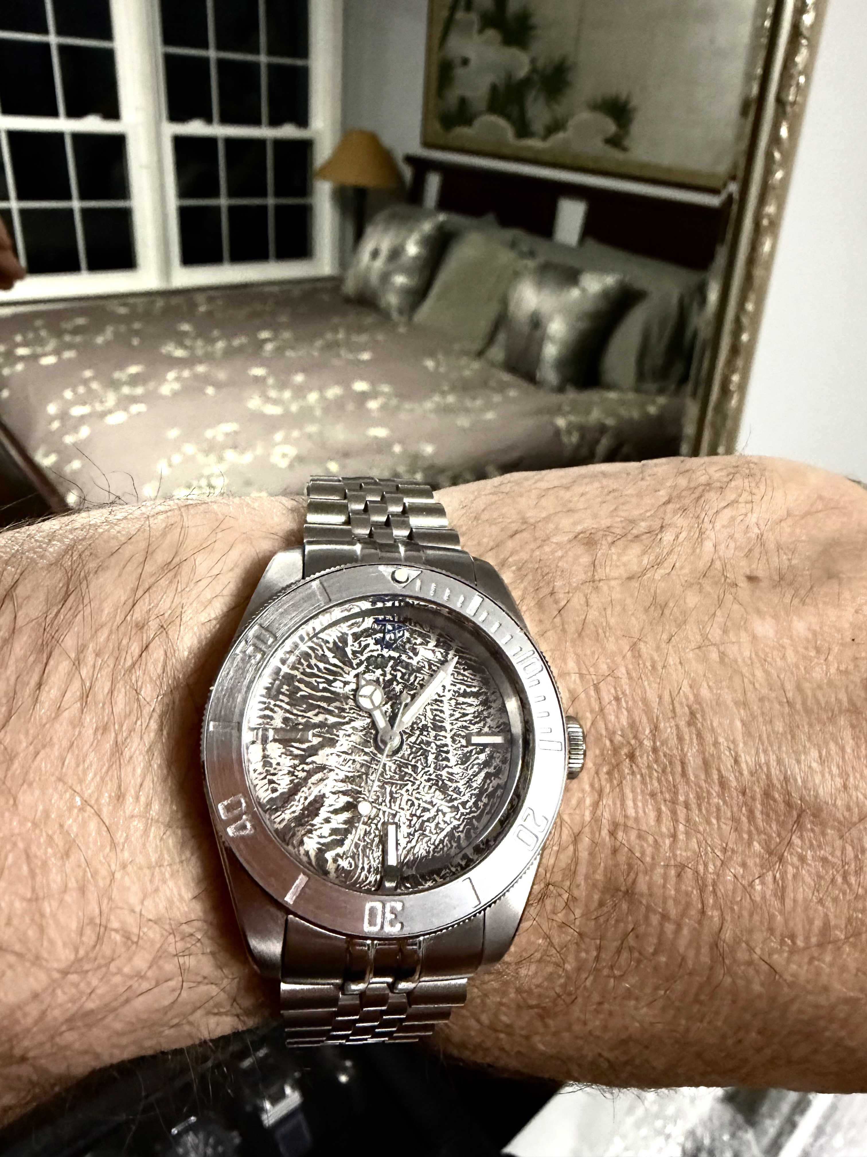 An uncoloured reticulated silver dial on a steel bracelet