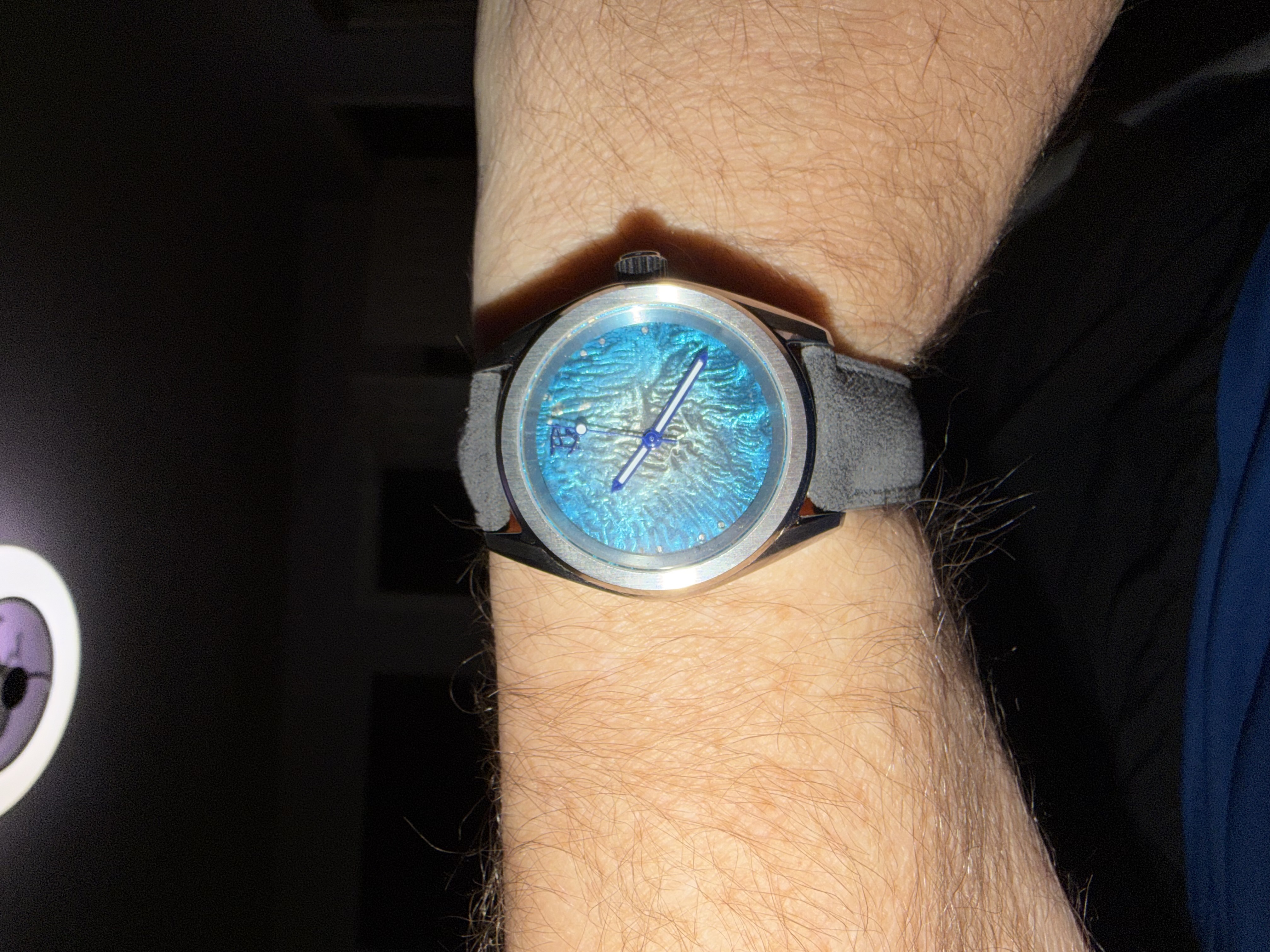 A luminous cyan dial in a steel case on grey suede