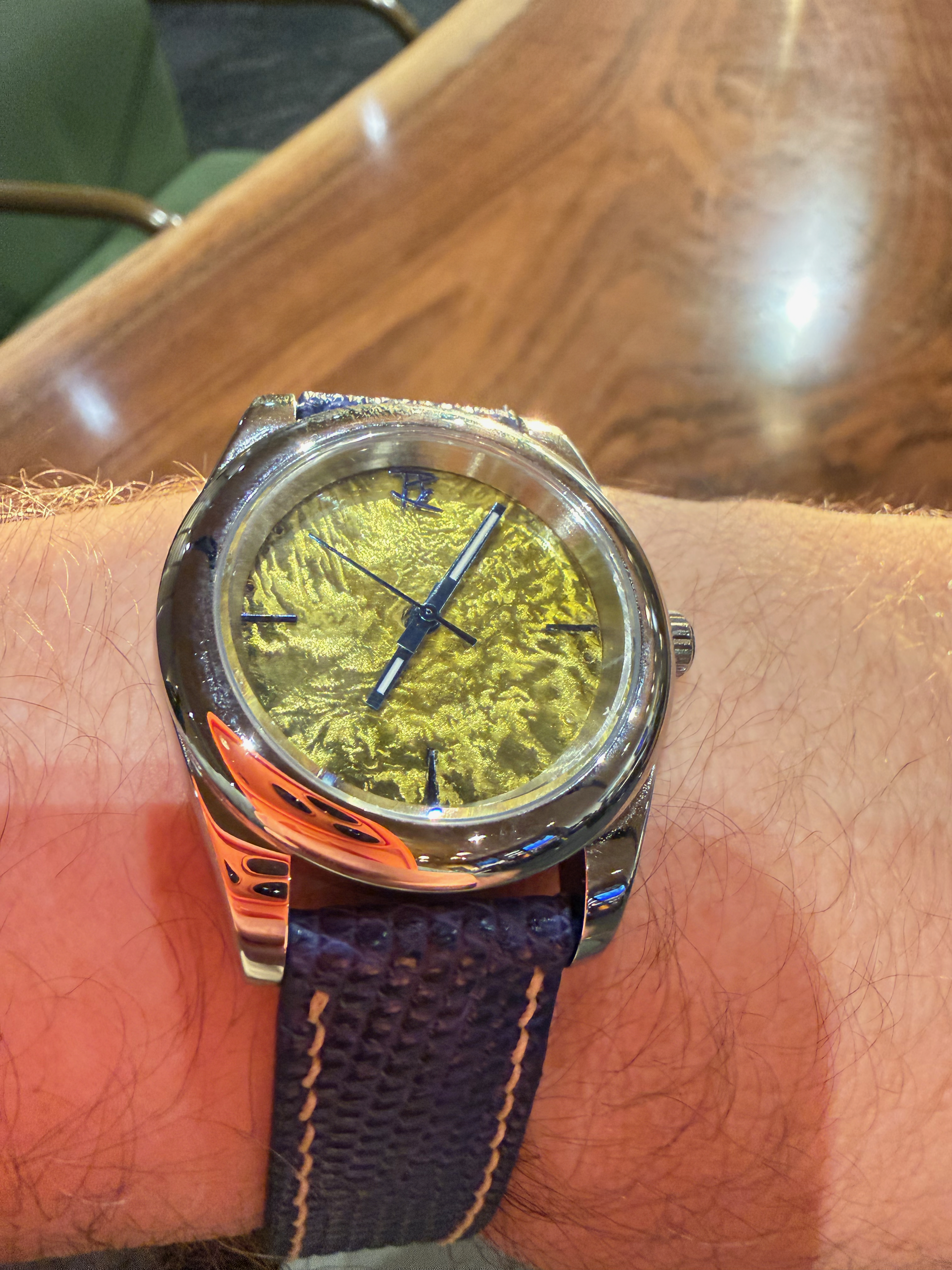 The gold reticulated dial on a navy lizard strap