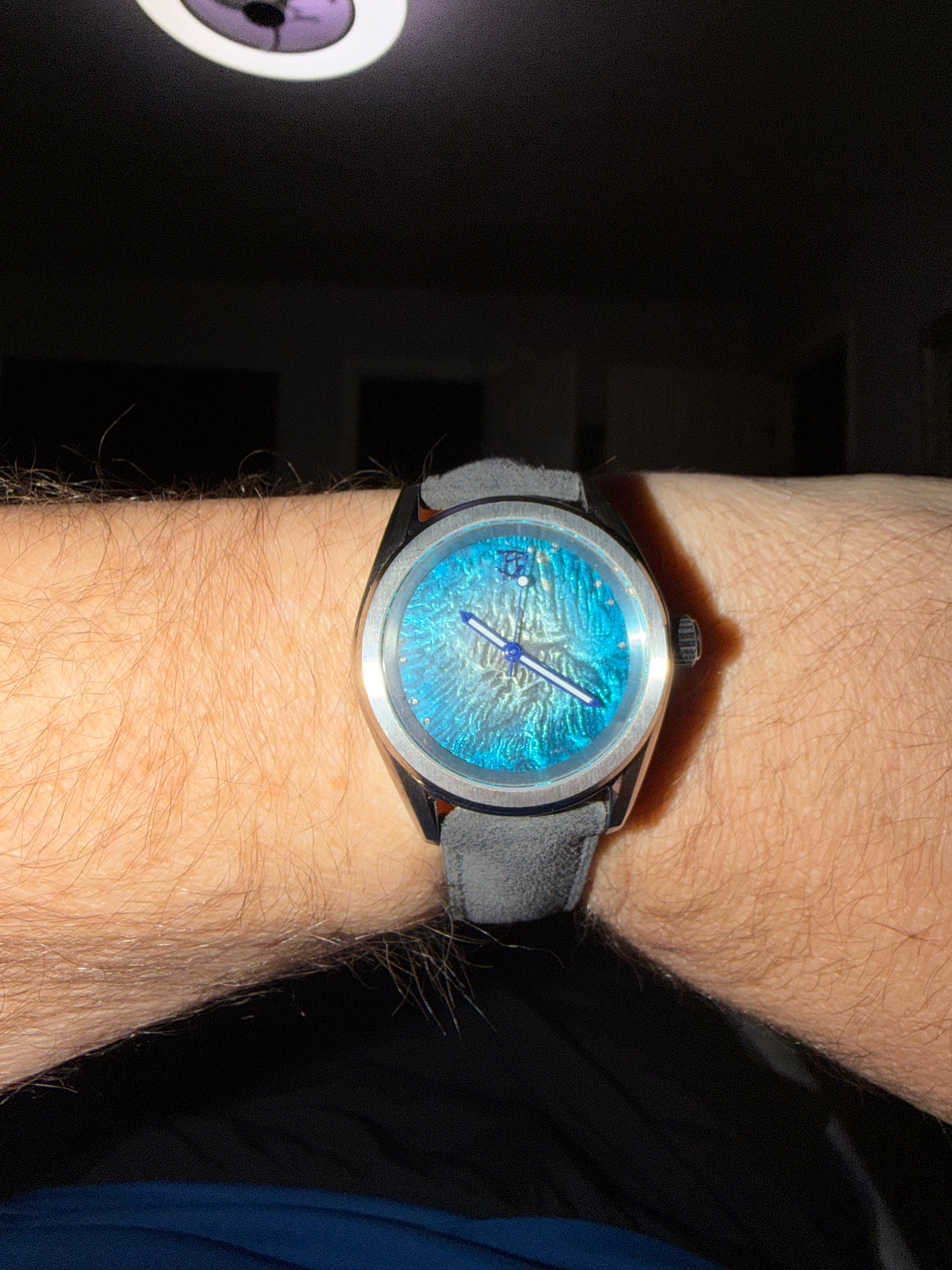 A small turquoise enamel dial on grey suede